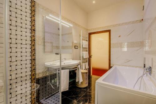 a white bathroom with a sink and a tub at Villa Lecchi Hotel Wellness in Colle Val D'Elsa