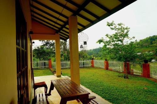 a porch with a wooden bench and a fence at Rose Villa by Kananke Hills in Kananke