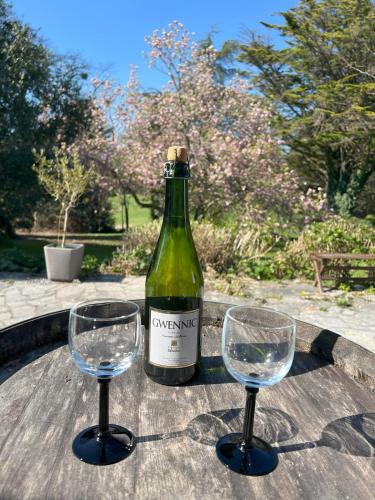 une bouteille de vin et deux verres à vin sur une table dans l'établissement Maison familiale au cœur du golf de Cornouaille, à La Forêt-Fouesnant