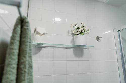 a glass shelf in a bathroom with a vase of flowers at Douro Garden - Authentic Portuguese Guesthouse in Vila Nova de Gaia