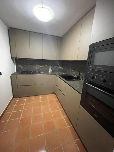 a kitchen with white cabinets and an orange tile floor at Villa con vista mare in Stalettì