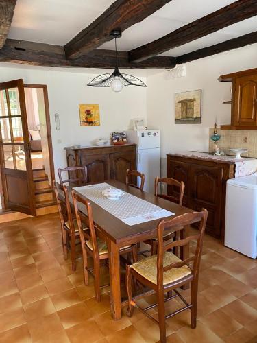 une cuisine avec une table, des chaises et un réfrigérateur dans l'établissement La Maison de Jeanne, à Tour-de-Faure