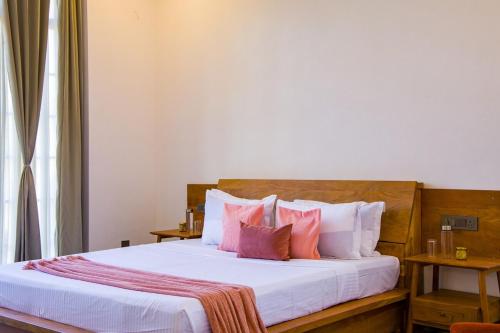 a bedroom with a bed with white sheets and pink pillows at Nature 95 by ELIVAAS 4 BHK Farm with Private Pool in Chandwaji