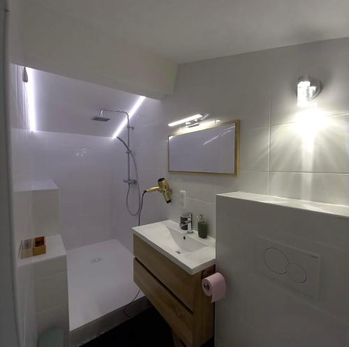 une salle de bain blanche avec un lavabo et un miroir dans l'établissement La Maunia Studio, à Montceaux
