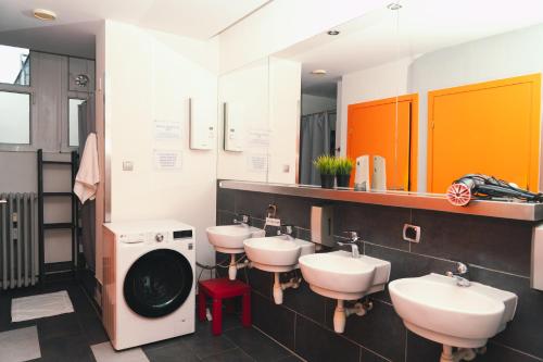 a bathroom with three sinks and a washing machine at LazeMaze Hostel in Krakow