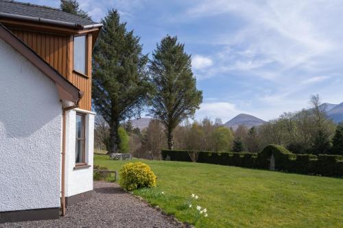 a house with a garden and mountains in the background at Mizpah Bed & Breakfast near Ben Nevis Highlands in Roybridge