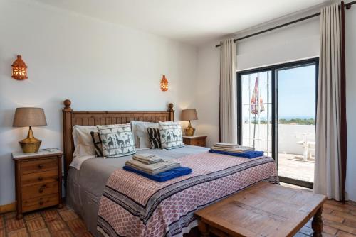 a bedroom with a bed and a large window at Elegant villa, beautiful ocean view, natural paradise! in Tavira