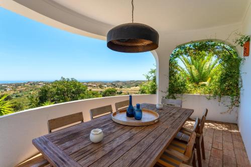 a wooden table and chairs on a balcony with a view at Elegant villa, beautiful ocean view, natural paradise! in Tavira
