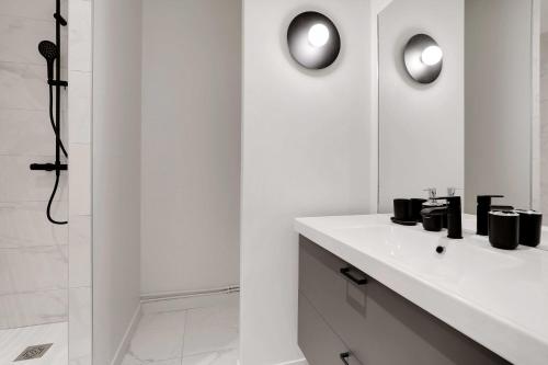 une salle de bain blanche avec un lavabo et une douche dans l'établissement Modern Apartment 1BR- 4P Le Marais Quarter, à Paris