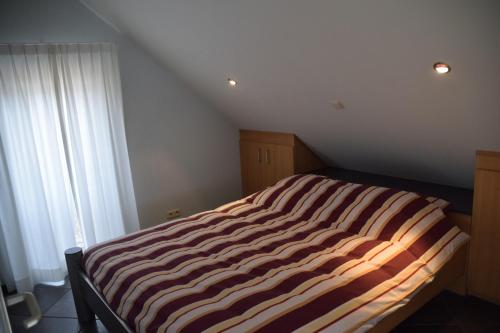 a striped bed in a room with a window at La Bordure de la Forêt in Sourbrodt