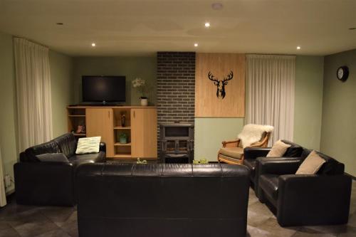 a living room with leather couches and a tv at La Bordure de la Forêt in Sourbrodt