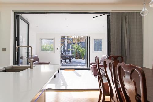 a kitchen with a white counter and wooden chairs at Unwind 2Bed with Garden, Sauna and Hot Tub in Barking