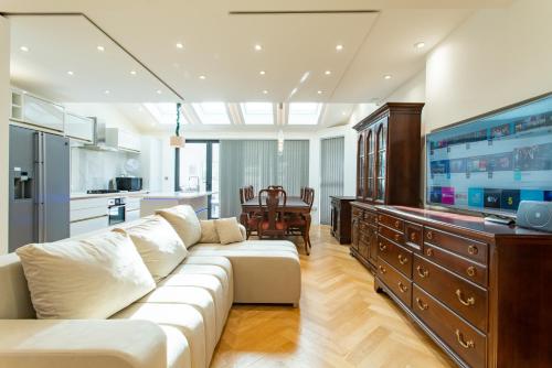 a living room with a white couch and a large tv at Unwind 2Bed with Garden, Sauna and Hot Tub in Barking
