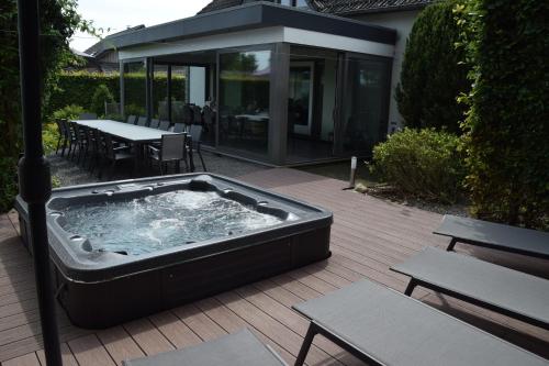 a hot tub on a deck with a table and benches at La Bordure de la Forêt in Sourbrodt