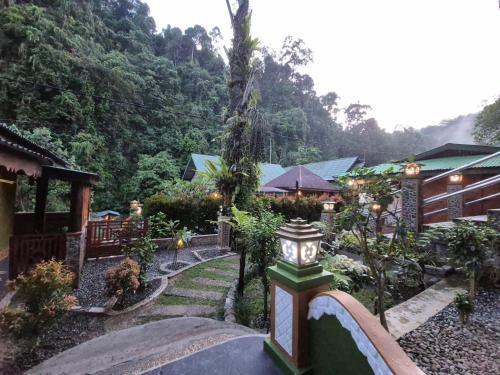 a garden with a clock in front of a building at Sam's Bungalows And Treks in Bukit Lawang