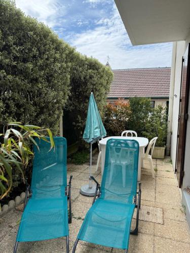 deux chaises, une table et un parasol sur une terrasse dans l'établissement Du côté de chez, à Houlgate