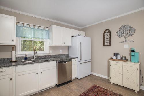a kitchen with white cabinets and a white refrigerator at Cardinal Seas home in Morehead City