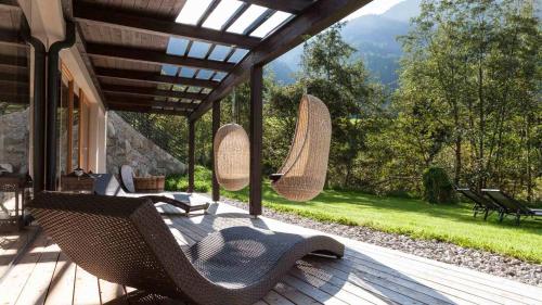 a porch with two wicker chairs on a deck at La Casies Mountain Hotel in Santa Maddalena in Casies