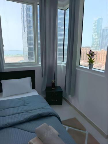a bedroom with a bed and two large windows at New Phenomenal Room with Sea View in Abu Dhabi
