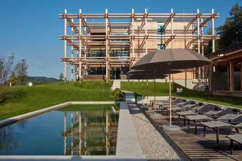 a pool with chairs and an umbrella next to a building at Hotel BERGEBLICK in Bad Tölz