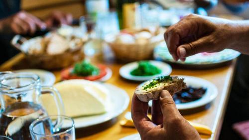 a person holding up a piece of food on a table at La Casies Mountain Hotel in Santa Maddalena in Casies