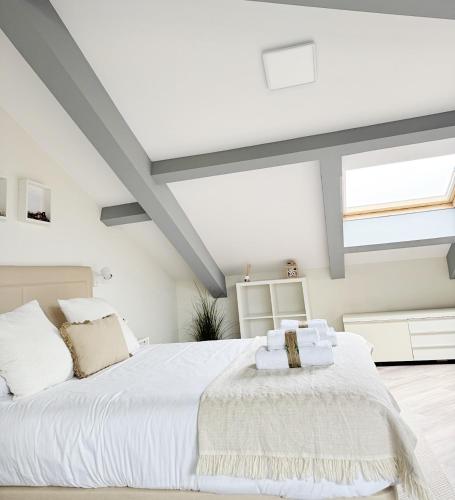 a white bedroom with a large bed and windows at Llanes Suites in Llanes