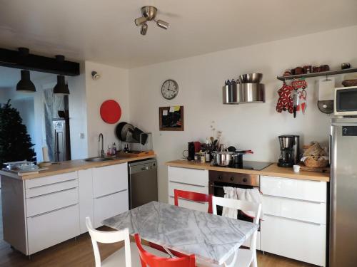 une cuisine avec des armoires blanches et une table avec des chaises dans l'établissement Spacious house, ideally located with pool!, à Rochefort