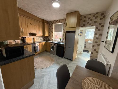 a kitchen with a refrigerator and a table with chairs at 3 bed Jct 37 M1 luxury stay! in Barnsley