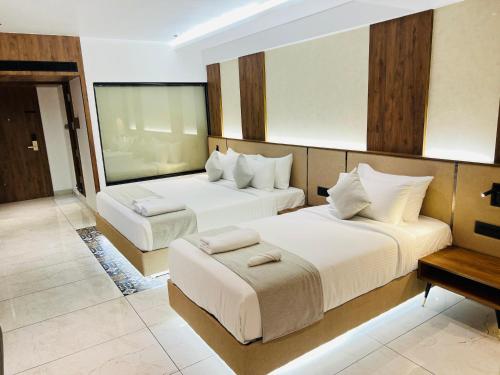 a hotel room with two beds and a table at Royal Plaza Inn by RAK Rooms, Calicut in Kozhikode