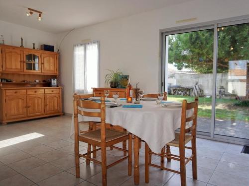 une salle à manger avec une table et des chaises et une cuisine dans l'établissement Maison cosy proche plage avec jardin clos et terrasse - FR-1-224B-735, à LʼÉpine