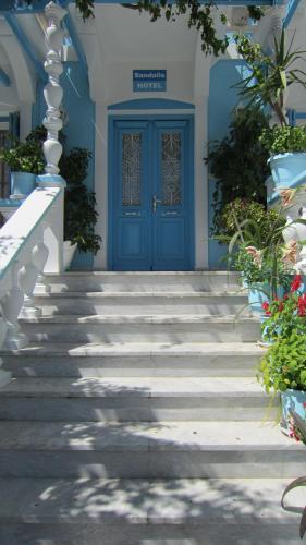 a blue door on a building with stairs at Sandalis Hotel in Pythagoreio