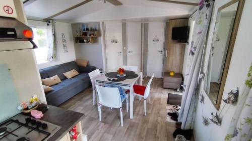 Ce petit appartement comprend une table et un canapé bleu. dans l'établissement Mobilhome, à Saint-Arnoult