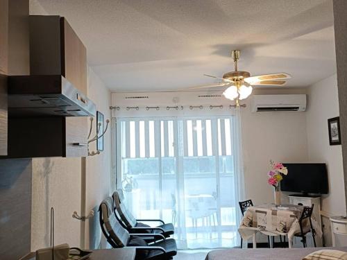 Il comprend un salon avec un ventilateur de plafond et une cuisine. dans l'établissement Studio rénové avec télévision, lave-linge, animaux admis - FR-1-680-23, à Balaruc-les-Bains