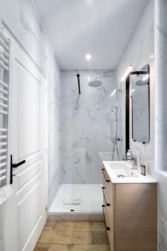 une salle de bain blanche avec une douche et un lavabo dans l'établissement Studio à 2 min métro 13 - accès Paris Champs-Élysées, à Asnières-sur-Seine