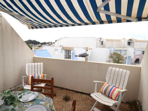 d'une terrasse avec 2 chaises et un oiseau sur un balcon. dans l'établissement Studio cabine refait à neuf avec terrasse, piscine, parking et lave-linge - Le Grau-du-Roi - FR-1-307-249, au Grau-du-Roi