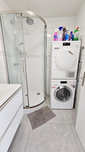 une salle de bain avec une machine à laver et un lave-linge dans l'établissement Appartement T3 à 5 min de Disney et 25min de Paris, à Bussy-Saint-Georges