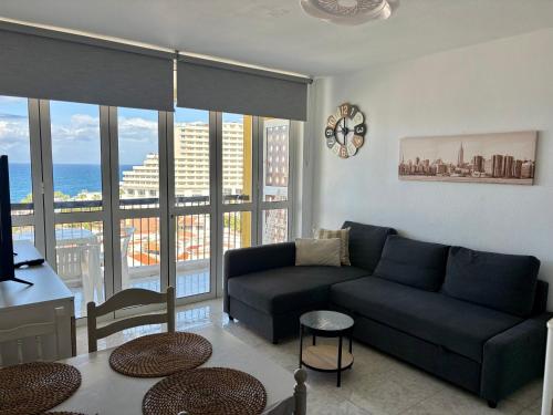 a living room with a couch and a large window at Rainbow Copacabana in Playa Fañabe