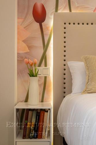 a vase with flowers on a book shelf next to a bed at Exclusive Apartment Center Gijón in Gijón