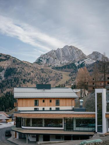 a large building with mountains in the background at Apartment Hotel Schneerose in Sonnenalpe Nassfeld