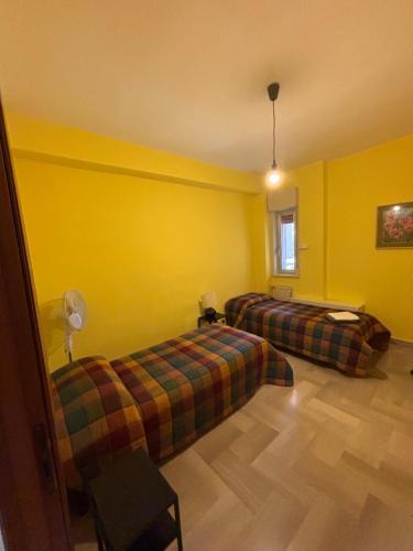 a room with two beds and yellow walls at Appartamento Vittoria in Grotte