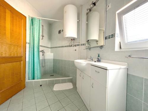 Un baño blanco con lavabo y ducha en Stella Maris, en Kukljica