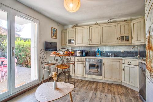 une cuisine avec des armoires blanches et une table et des chaises dans l'établissement Les Dunes - Jardin Privatif - Plage à 500 Mètres, à Merville-Franceville-Plage