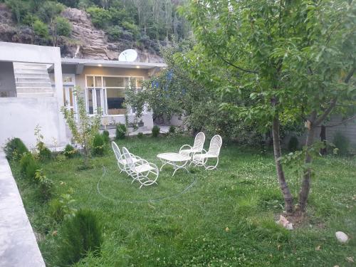 a yard with chairs and a table and a tree at Mountain Villa - Hunza Valley in Hunza