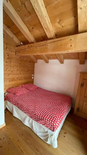 a red bed in a room with wooden ceilings at Chalet ChampBenoit in Valmorel