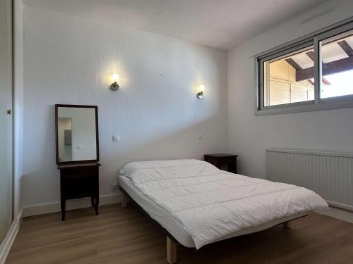 une chambre blanche avec un lit et un miroir dans l'établissement Appartement 4 couchages, terrasse, parking, animaux admis - Banyuls-sur-Mer - FR-1-225C-99, à Banyuls-sur-Mer