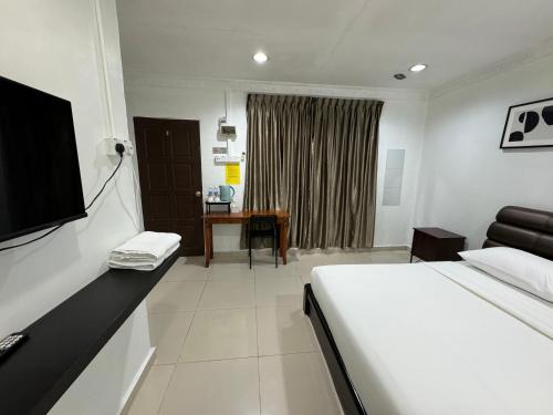a bedroom with a bed and a desk with a television at Lan Village in Mersing