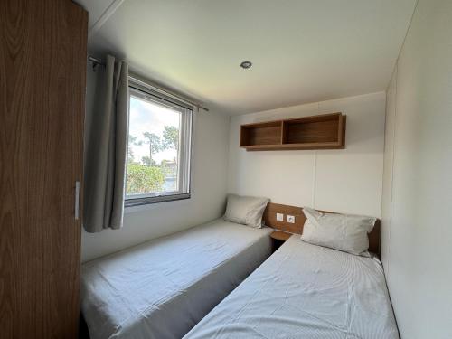 deux lits dans une petite pièce avec une fenêtre dans l'établissement Bungalow moderne vue bassin les viviers Cap-ferret, à Lège-Cap-Ferret