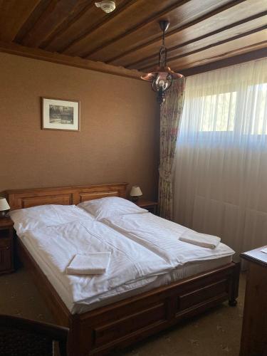 a bedroom with a bed with white sheets and a window at Wellness Hotel Encian Donovaly in Donovaly