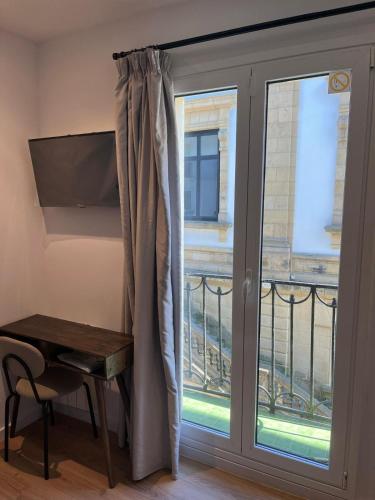 サン・セバスティアンにあるKaixo Roomsのガラスのスライドドア(バルコニーの横にデスク付)