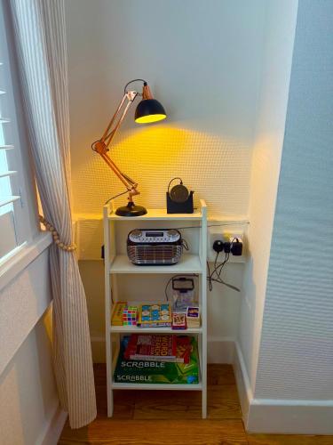 a small white shelf with a lamp on top of it at Bloom19 Traditional Belfast Entire House 10 mins from City Centre in Belfast